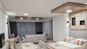 A modern hotel room with a sofa set, a dining table with chairs, a bed with a headboard, a TV, and a window with curtains. - Aparthotel Centar Sarajevo (Sarajevo)