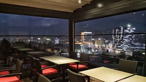 A rooftop restaurant with tables and chairs, offering a view of a cityscape at night. - Aparthotel Centar Sarajevo (Sarajevo)