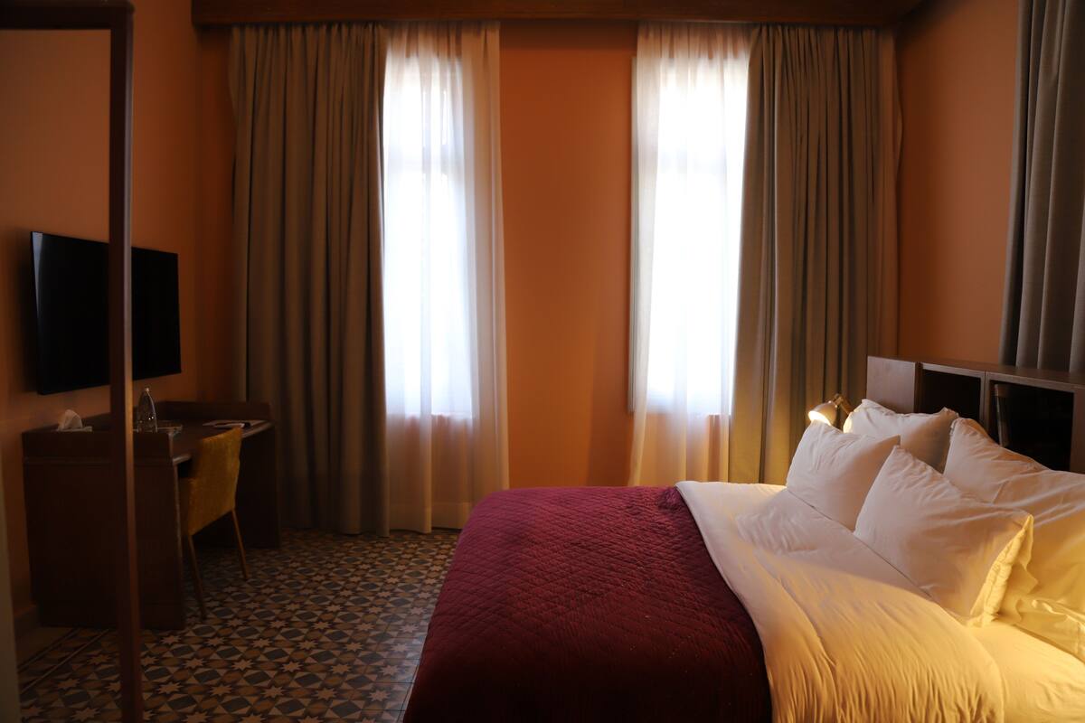 Hotellihuone, jossa on sänky, työpöytä, tuoli ja televisio.
