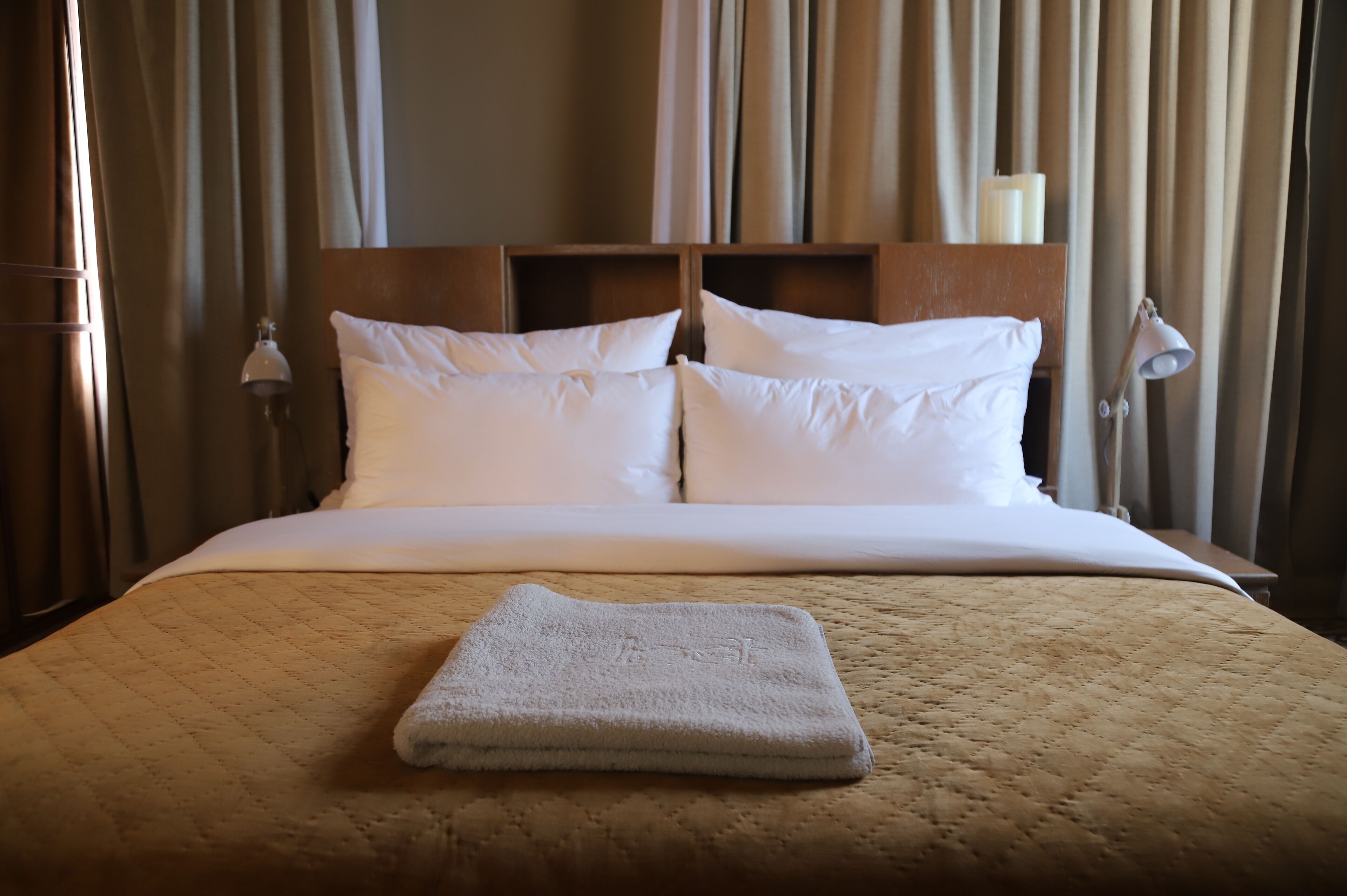 A neatly made bed with a quilted bedspread, two pillows, and a folded towel on the bed.