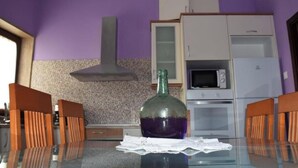A kitchen with purple walls, a gas stove, a microwave, and a refrigerator.