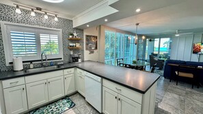 A modern kitchen with a central island, a dining area with a view, and a living space with a TV.