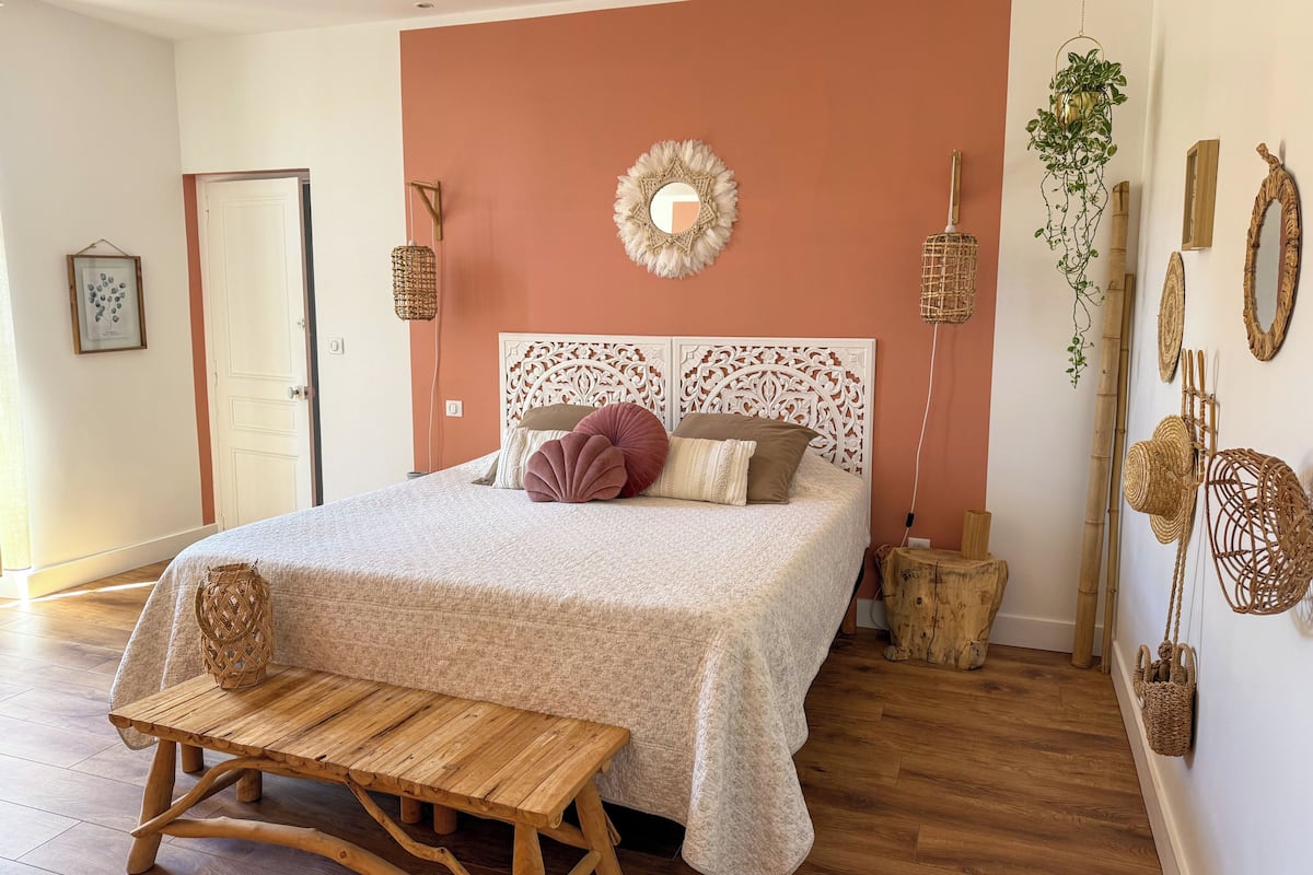 A bedroom with a bed, bedside tables, a wooden bench, and decorative items.