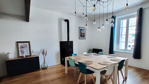 Un comedor con mesa de madera, sillas color turquesa y estufa negra.