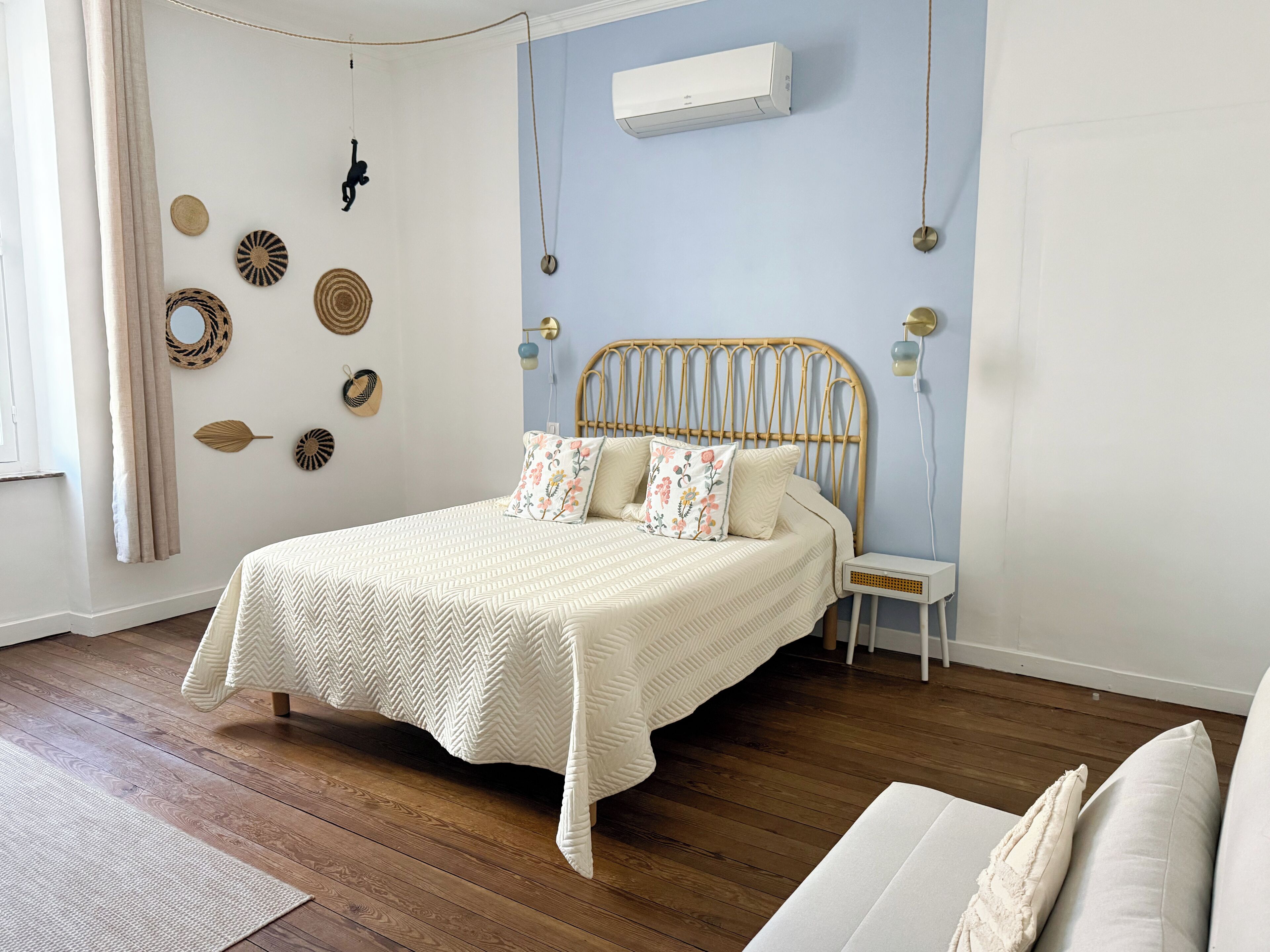 Ein ordentlich eingerichtetes Schlafzimmer mit Bett, Nachttisch und Wandgerät zur Klimatisierung.