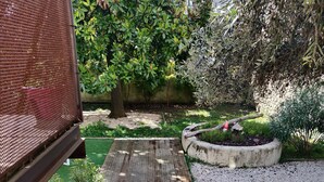 Una escalera conduce a un jardín con terraza de madera, caminos de grava y diversas plantas.