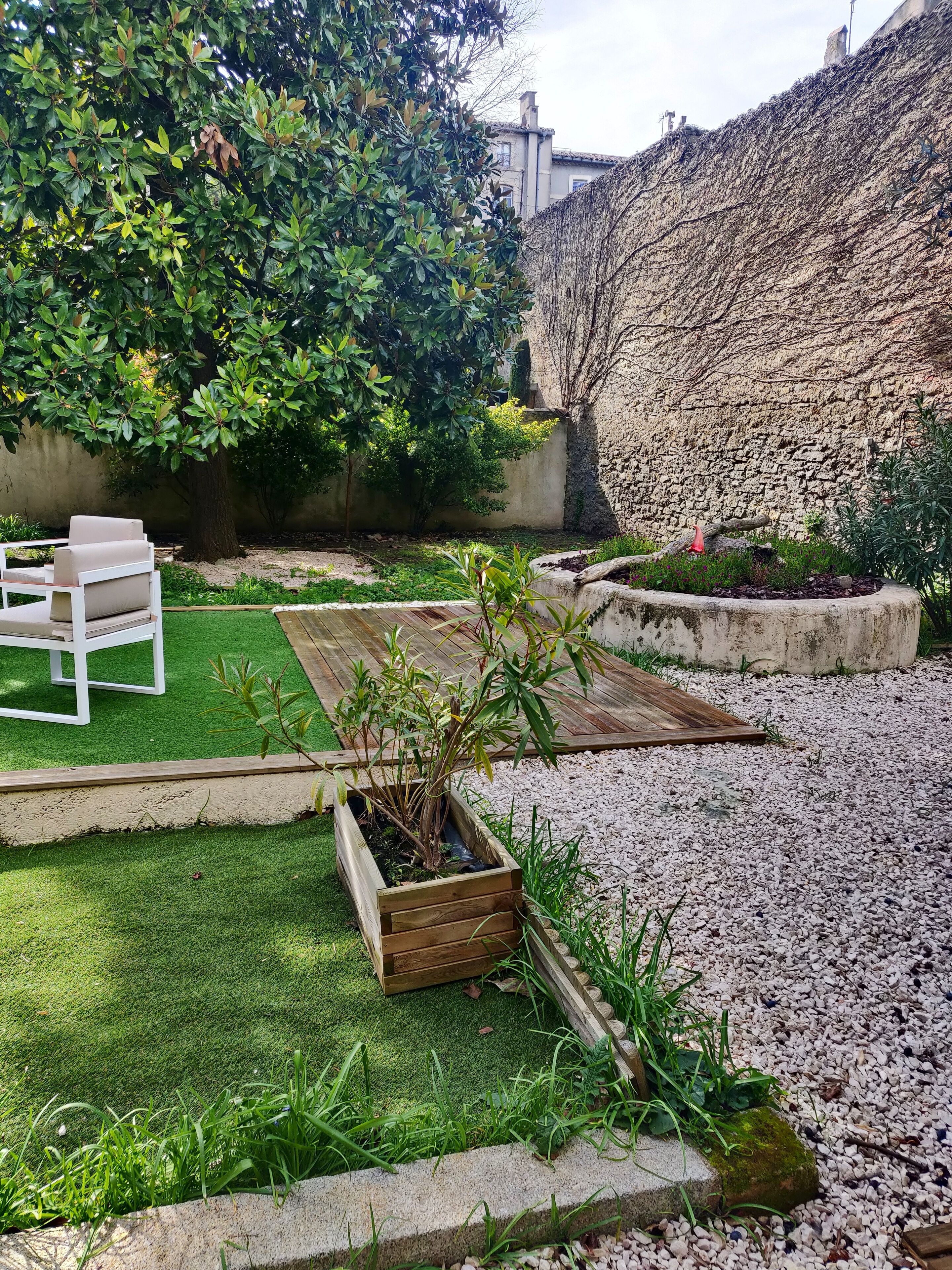 A garden with a wooden bench, a planter box, and a grassy area.