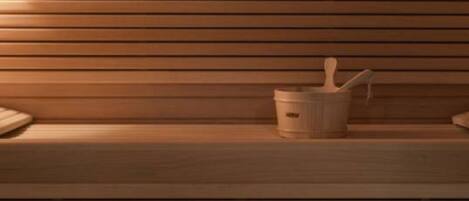 A wooden bench with a small bucket and a spoon, likely for a sauna or steam room.