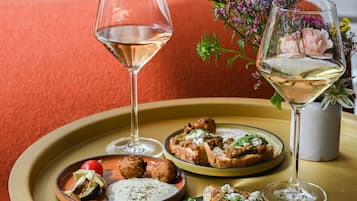 Une table à manger avec deux assiettes de nourriture et deux verres de vin blanc, le tout sur un fond rouge.