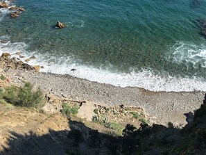 Une plage rocheuse avec une eau claire et des vagues qui déferlent sur le rivage.