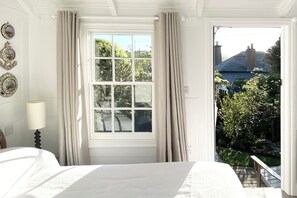 Een slaapkamer met een groot raam, een bed en een nachtkastje.