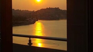 A sunset view from a window overlooking a body of water with a distant shoreline. - "VERDE BLUE" – Stylish Loft with Panoramic Terrace in Kavala (Kavala)