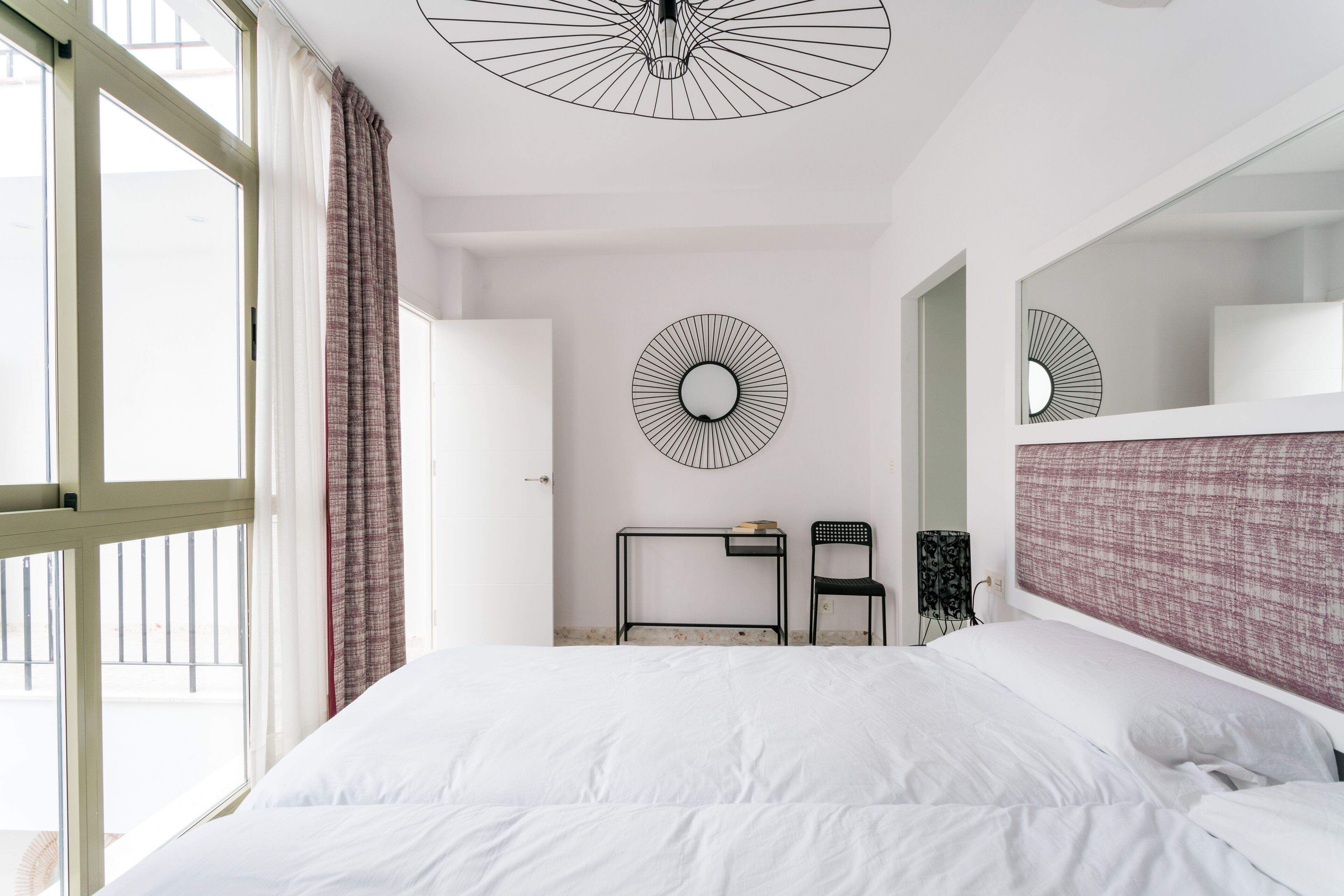Een slaapkamer met een groot bed, een bureau, een stoel en een ronde wanddecoratie.