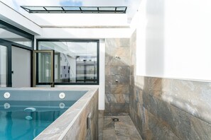 A modern bathroom with a glass-enclosed shower, a built-in bathtub, and stone-tiled walls. - Casa Pedro. 5 bedrooms, 5 bathrooms, private pool (Sevilla)