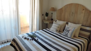 A bedroom with a checkered bedspread, a wooden headboard, and decorative pillows with text.