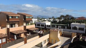A residential area with multiple buildings, including a two-story house with a tiled roof and a flat-roofed building with a balcony.