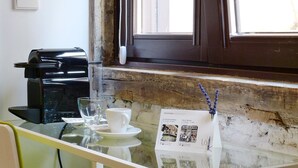 A small table with a glass top, a white cup, a saucer, a black device, and a menu. - Pensión Lo Bilbao (Bilbao)
