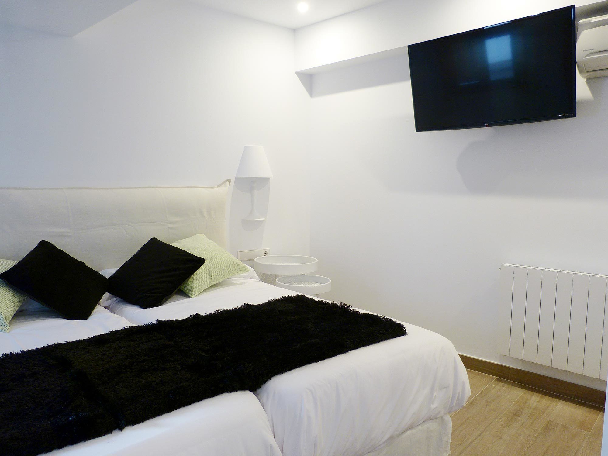 Une chambre d’hôtel moderne équipée d’un lit, d’un téléviseur à écran plat fixé au mur, d’une table de chevet et d’un radiateur.