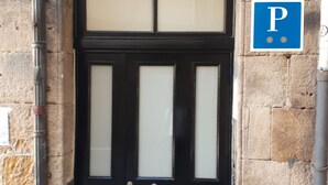 A black double door with a number 3 sign above it, a blue parking sign to the right, and stone walls. - Pensión Lo Bilbao (Bilbao)