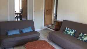 Ein Wohnzimmer mit zwei Sofas, einem Couchtisch und einer Holztür, die zu einer Treppe führt.