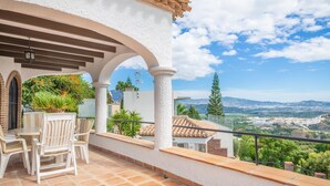Una terrazza con colonne bianche, un tavolo con sedie e vista sulla campagna.