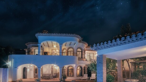 Un'ampia casa a più piani con piscina, area salotto all'aperto e patio ben illuminato.