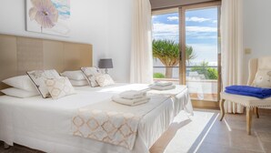 Camera d'albergo con un letto grande, una poltrona e un balcone con vista.