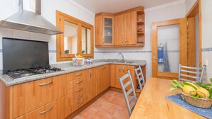 A compact kitchen with wooden cabinets, a gas stove, and a sink. - LLAC GRAN - Chalet with terrace in Port d'Alcudia. Free WiFi (Port d´Alcudia)