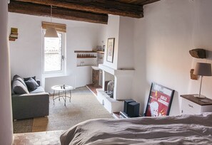 Um quarto aconchegante com uma cama, um sofá, uma mesinha e uma lareira.