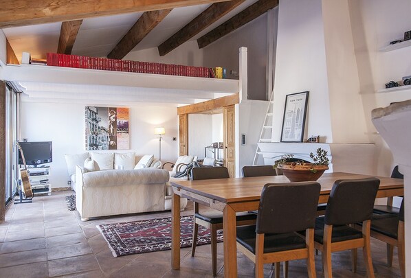 Uma sala ampla com mesa de jantar, cadeiras, sofá e televisão.