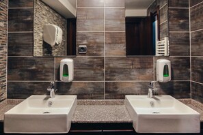 A bathroom with two sinks, a hand dryer, and a mirror.