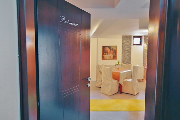 Un comedor moderno con una puerta de madera con la etiqueta “Restaurant”, una mesa con sillas y una alfombra amarilla.
