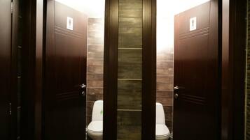 Eine Herrentoilette mit zwei Toiletten, Holztüren und einer gefliesten Wand.