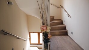A wooden staircase with a handrail, a vase with flowers, and a window at the top. - Hotel Bulevar (Bitola)
