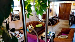 A living room with a sofa, armchairs, a coffee table, and a bookshelf. - Hotel Bulevar (Bitola)