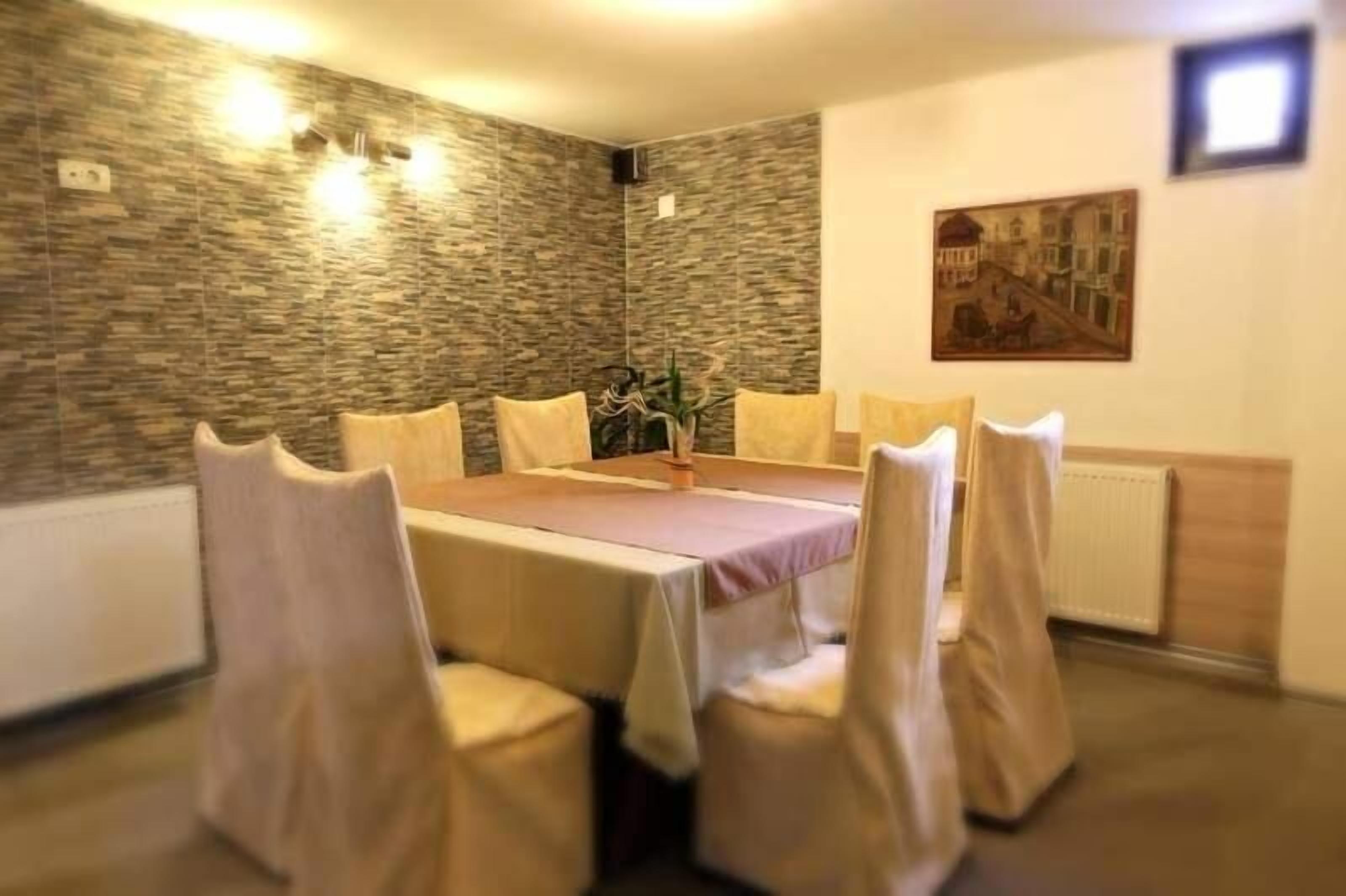 A dining area with a rectangular table, six chairs, a vase with flowers, and a painting on the wall.