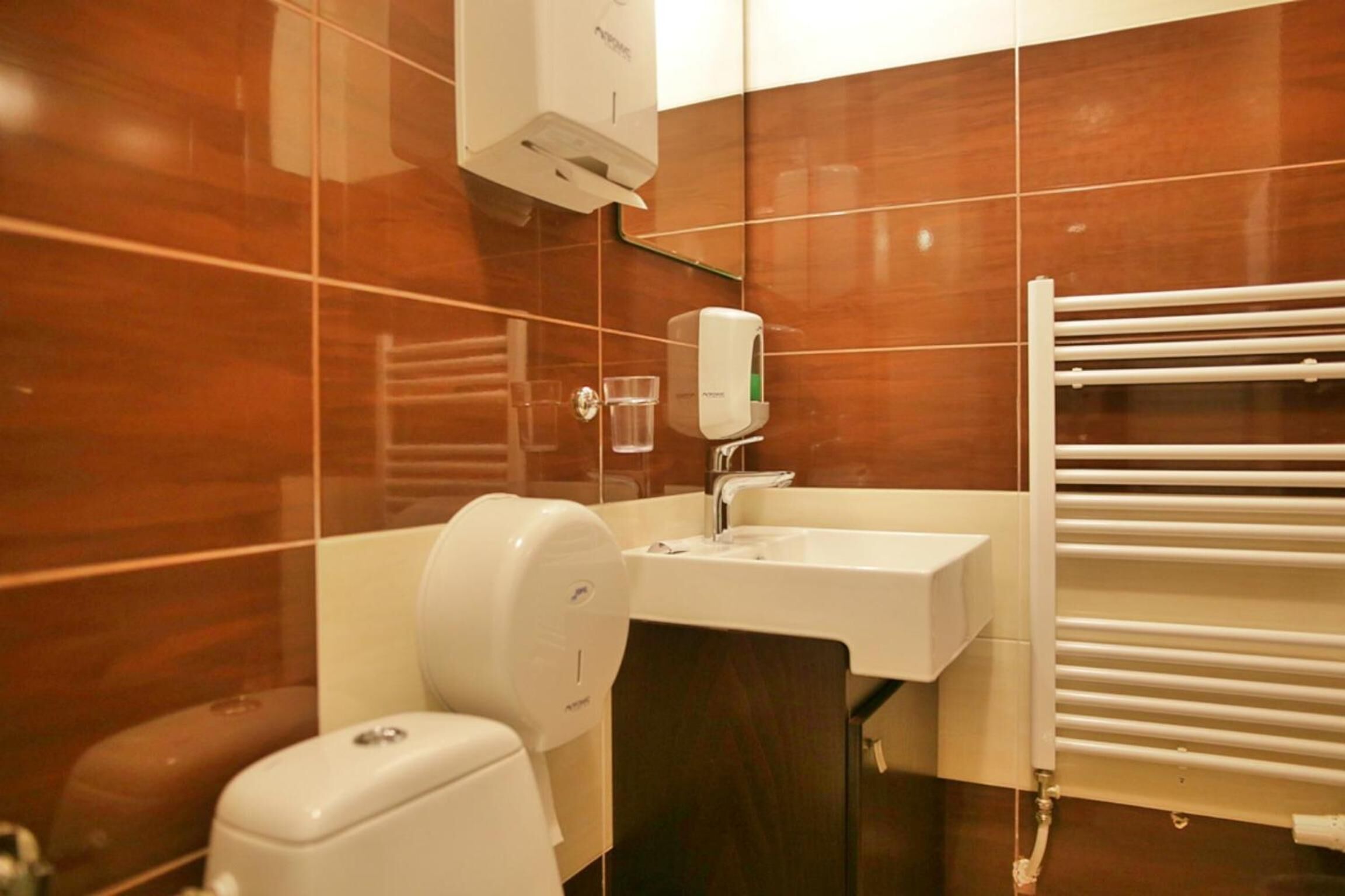 A bathroom with a toilet, sink, and hand dryer.