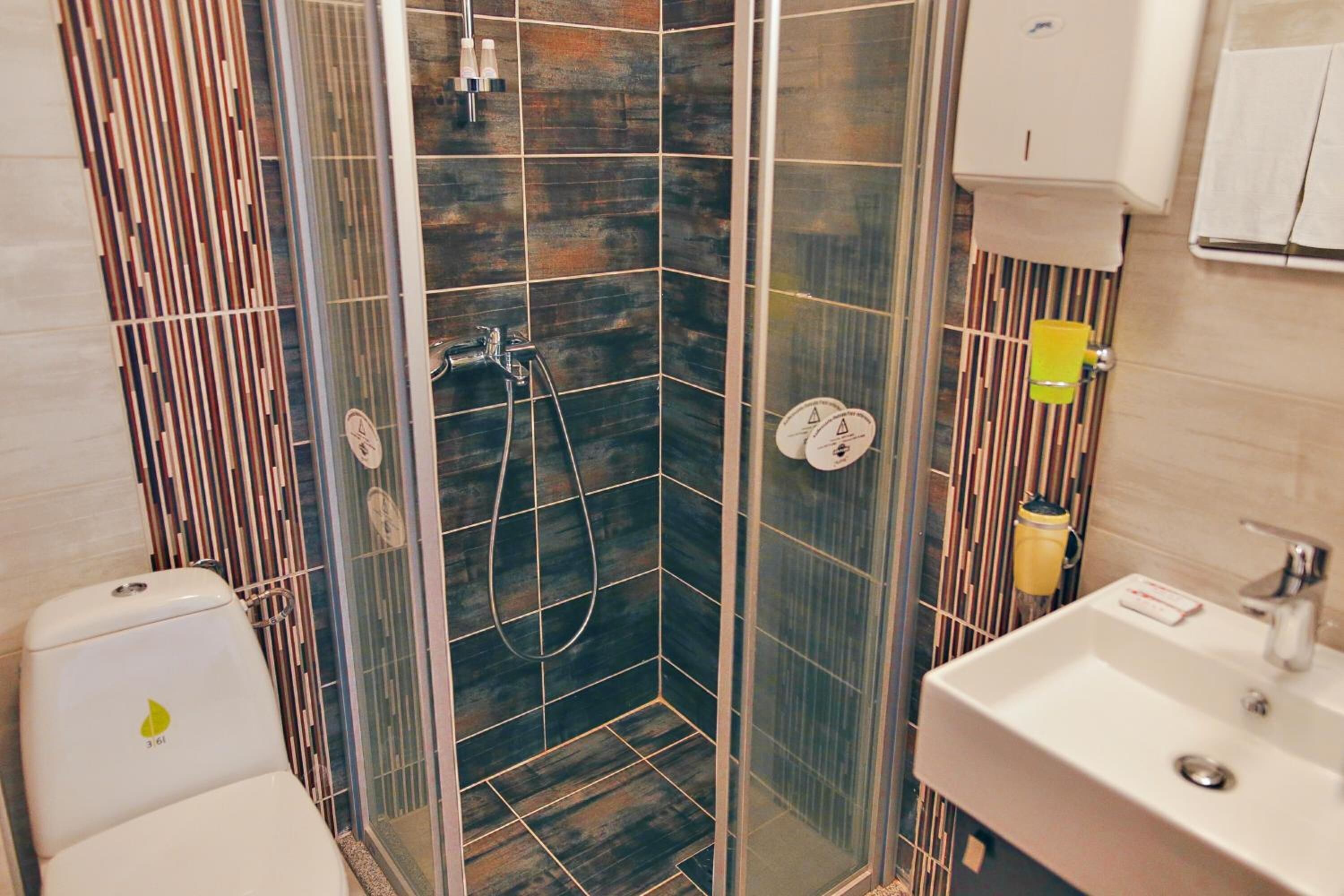 A modern bathroom with a glass-enclosed shower, a white sink, and a toilet.