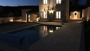 A two-story house with a swimming pool, outdoor lighting, and a gated entrance. - Beautiful new villa with garden and pool between vineyards and scrubland (Argilliers)
