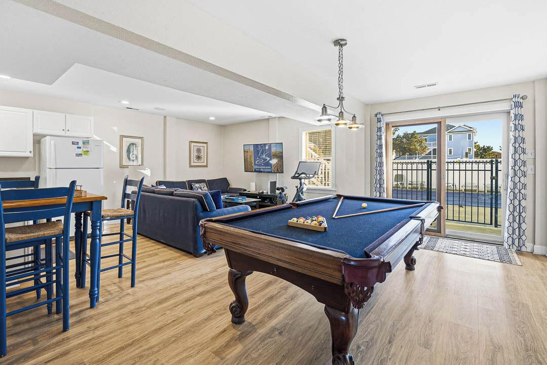 A pool table in a living room with a sofa and a dining table.