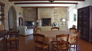 A spacious living room with a stone fireplace, a television, and a dining area with a table and chairs. - Villa with private pool, sea view and beautiful beaches within walking distance. (Sarzeau)