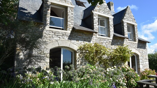 A stone building with multiple windows and a garden with various plants. - Villa with private pool, sea view and beautiful beaches within walking distance. (Sarzeau)