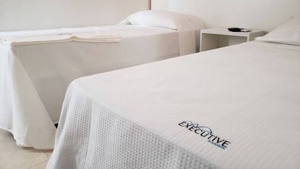 Een hotelkamer met twee bedden, een nachtkastje en een hoofdeinde.