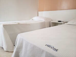 Een hotelkamer met twee bedden, een nachtkastje en een hoofdeinde.
