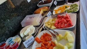 Een buffet met diverse gerechten, waaronder fruit, groenten en gebak.