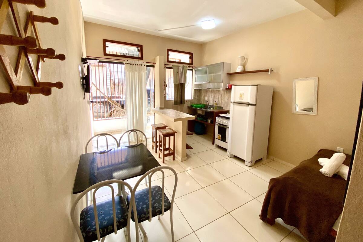 A compact kitchen with a dining area, including a table with chairs, a refrigerator, and a stove.