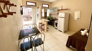 Uma cozinha compacta com área de refeições, incluindo uma mesa com cadeiras, geladeira e fogão.