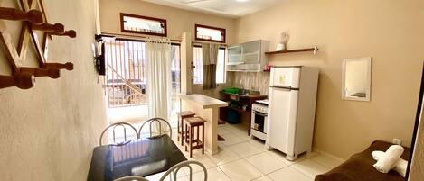 A compact kitchen with a dining area, including a table with chairs, a refrigerator, and a stove.