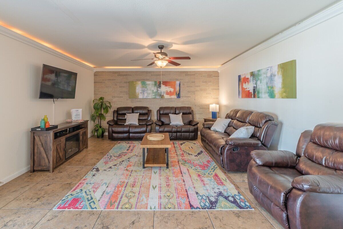 A living room with a ceiling fan, two leather sofas, a coffee table, and a colorful rug.