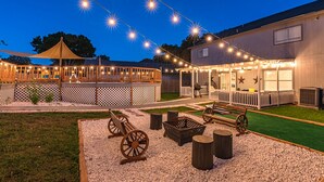 An outdoor patio area with string lights, wooden furniture, and a covered seating area.